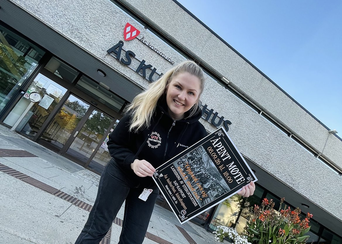 Utekontakten holder opp en plakat med info om arrangementet